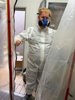 Abgeschotteter Sanierungsbereich mit Mitarbeiter in voller PSA. Abgeschotteter Arbeitsbereich mit Mitarbeiter in vollständiger persönlicher Schutzausrüstung.
