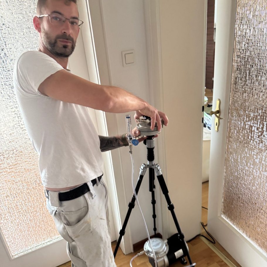 Mitarbeiter beim Einrichten eines Luftprobensammlers auf einem Stativ zur Untersuchung der Raumluft.