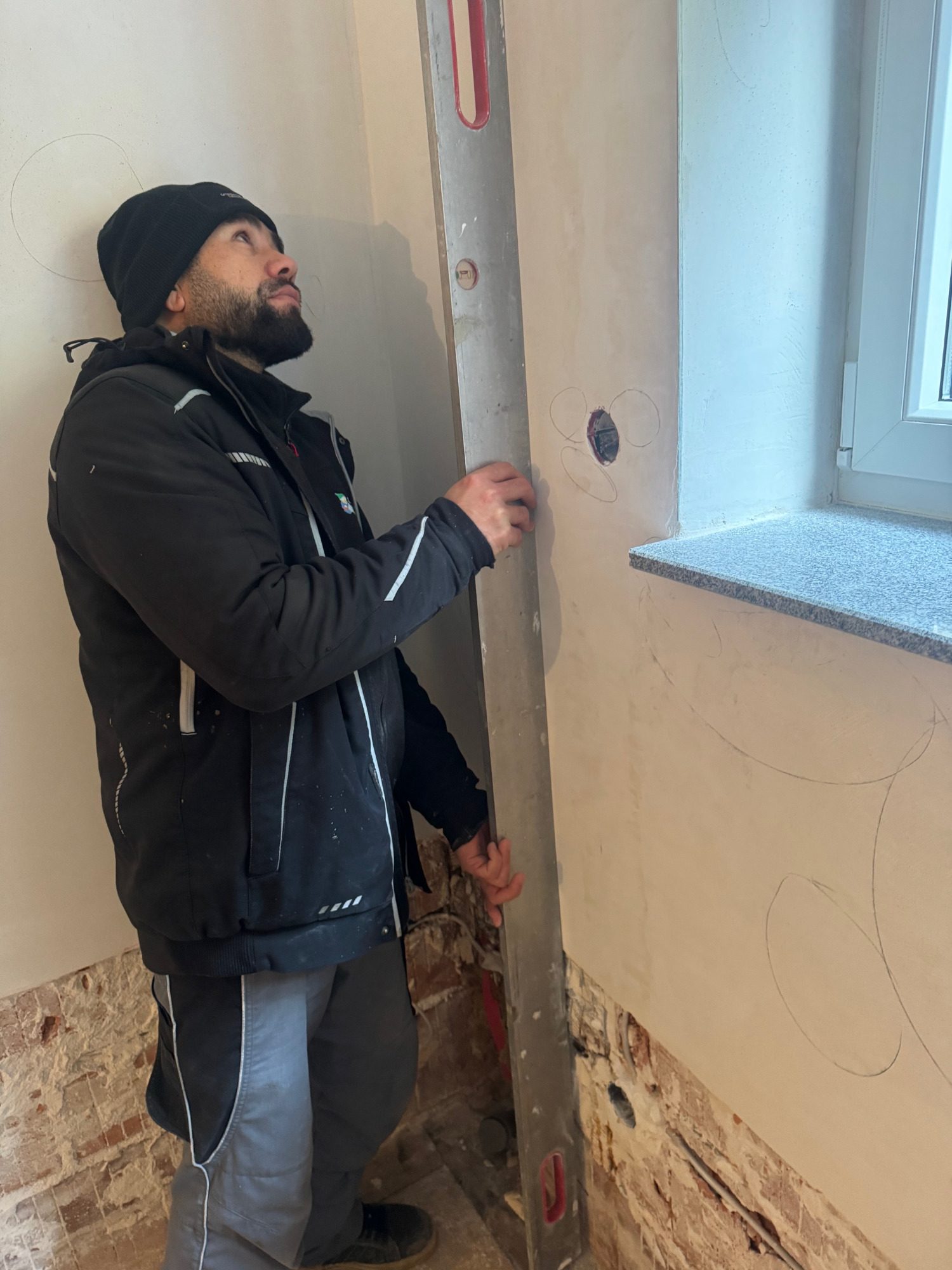 Ein Handwerker benutzt eine Wasserwaage an einer Wand.
