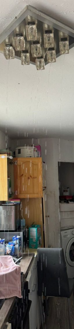 Wasser tritt aus einer Deckenlampe nach einem Wasserschaden aus.