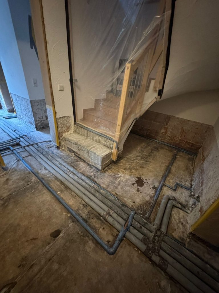 Kellerraum nach Rückstauschaden mit entferntem Estrich und abgeschlagenem Putz.