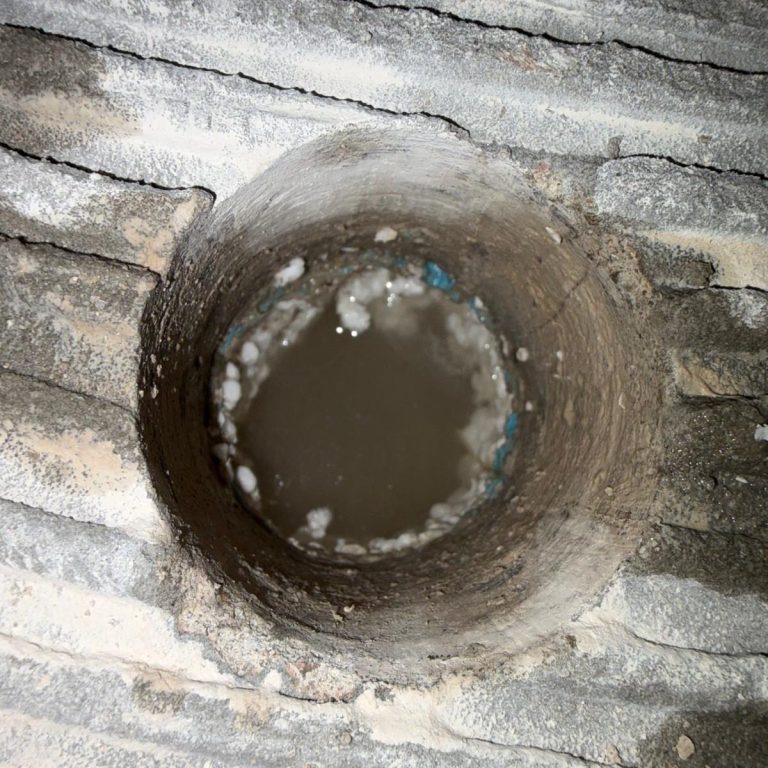 Stehendes Wasser in der Dämmschicht unter dem Estrich nach einem Wasserschaden.