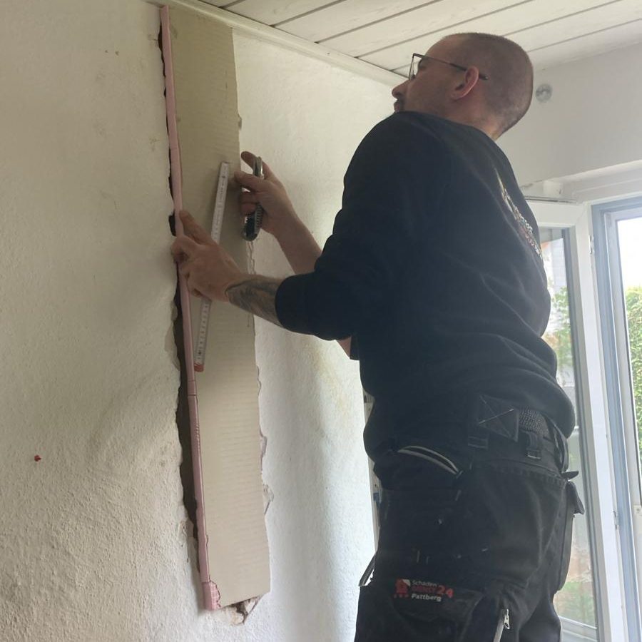 Mitarbeiter beim Einpassen einer Bauplatte in eine geöffnete Wandfläche.