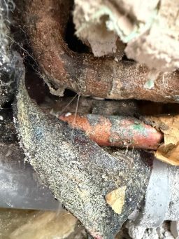 Wasser spritzt aus einer undichten Lötstelle an einem Kupferrohr.