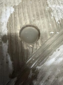Freies Wasser in der Dämmschicht, sichtbar in einer Bohröffnung des Estrichs. Hoher Wasserstand in einer Estrichbohrung bei der Prüfung einer durchfeuchteten Dämmschicht.