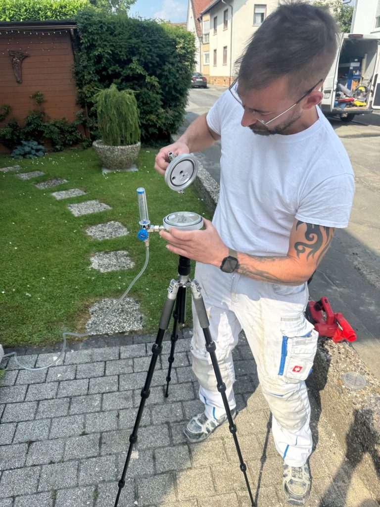 Mitarbeiter bei der Entnahme einer Raumluftprobe auf einer Petrischale zur Untersuchung auf Schimmelsporen.
